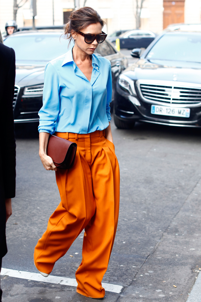 Виктория Бекхэм в оранжевых брюках и голубой рубашке